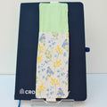Handmade A5 fabric notebook pen pocket in pale blue and yellow florals on white, white elastic — Dark Star Stitches