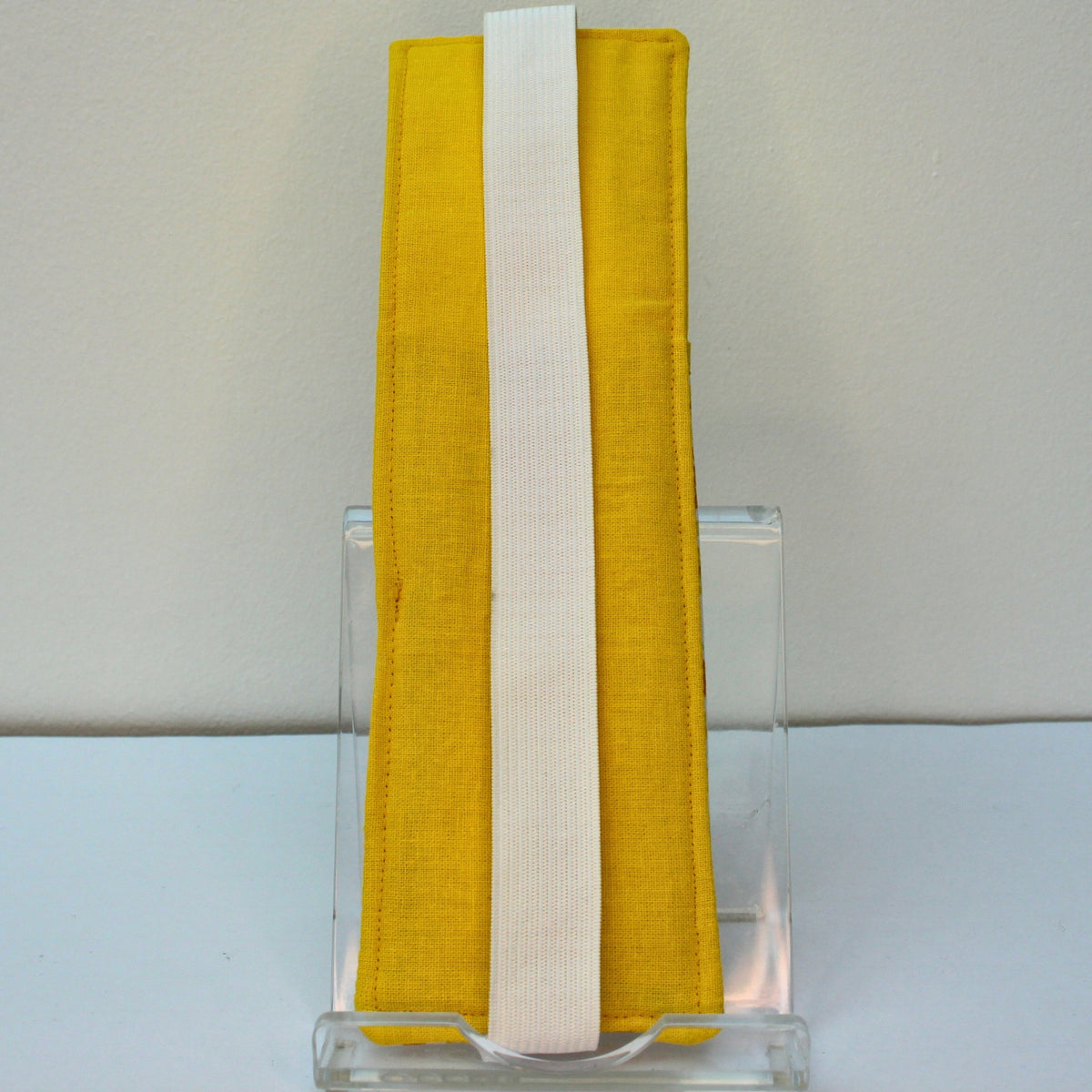 Reverse of handmade A5 fabric notebook pen pocket in yellow and orange floral, white elastic — Dark Star Stitches