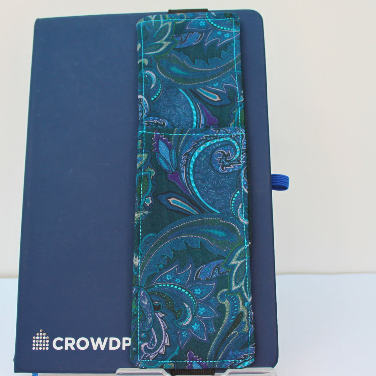 Handmade A5 fabric notebook pen pocket in electric blue and pink paisley on green, black elastic — Dark Star Stitches