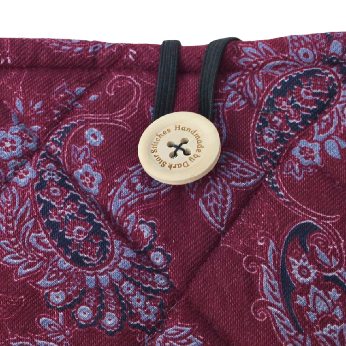 Close-up of button closure on handmade quilted booksleeve in burgundy and grey paisley fabric