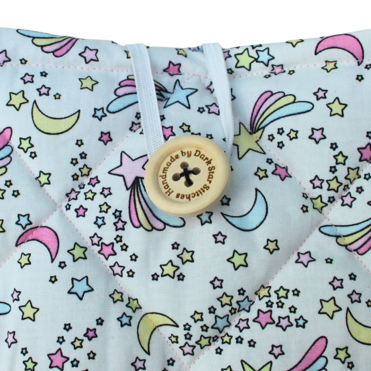 Close-up of button closure on handmade quilted booksleeve in pastel moons and stars fabric