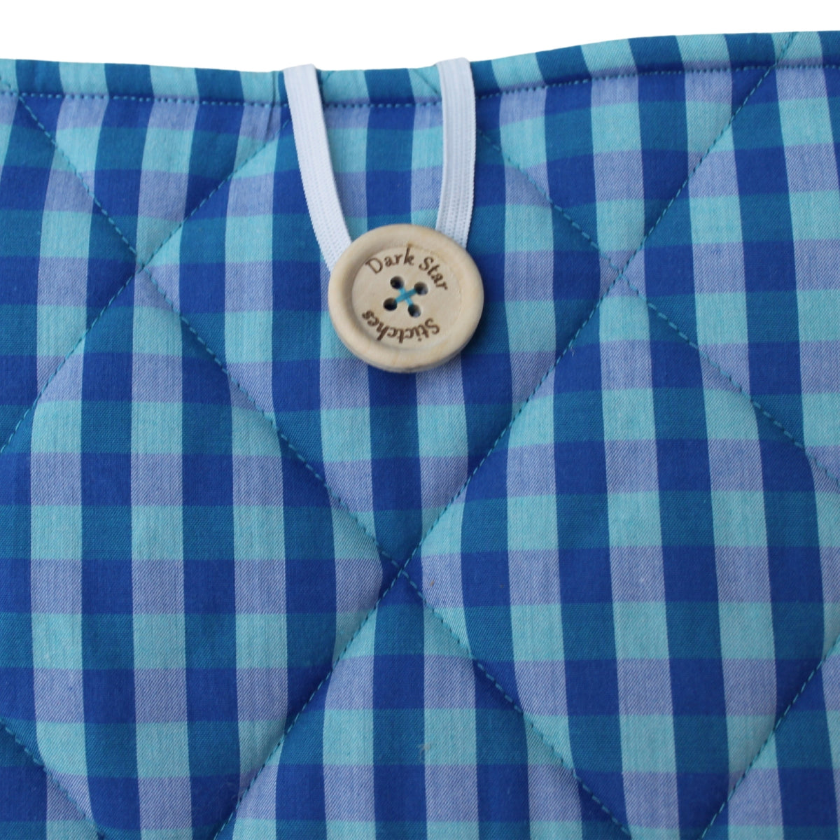 Close-up of button closure on handmade quilted booksleeve in light and dark blue check fabric