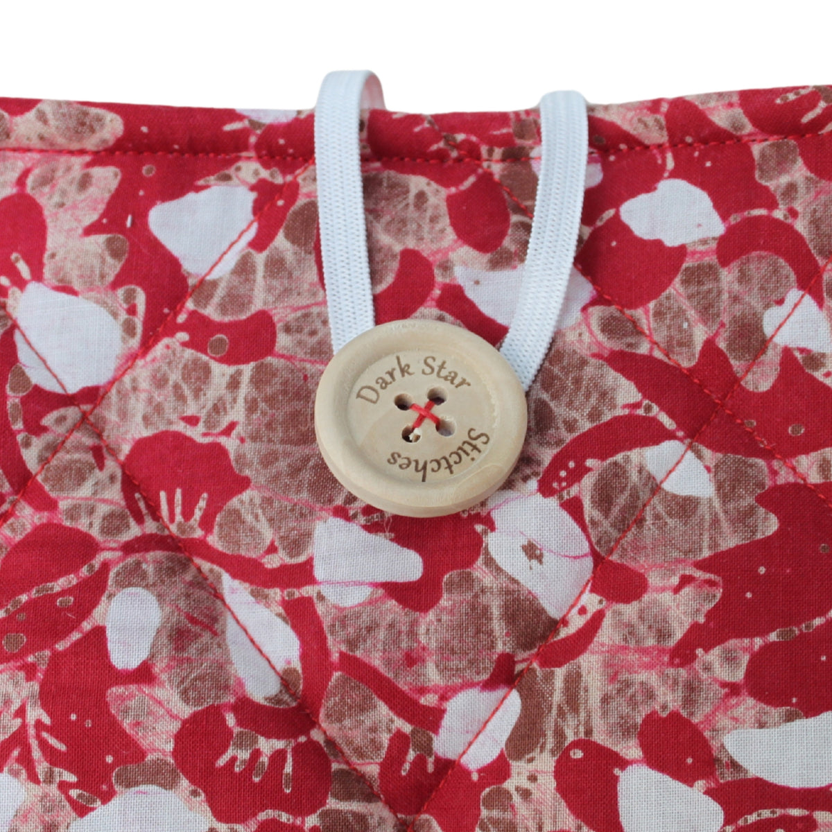 Close-up of button closure on handmade quilted booksleeve in red, brown and white patterned fabric