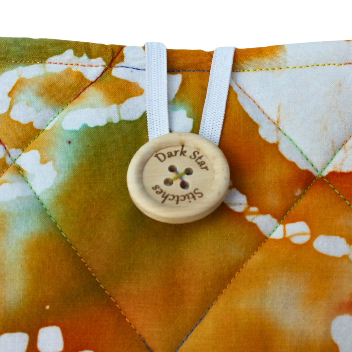 Close-up of button closure on handmade quilted booksleeve in tie dye patterned cotton fabric