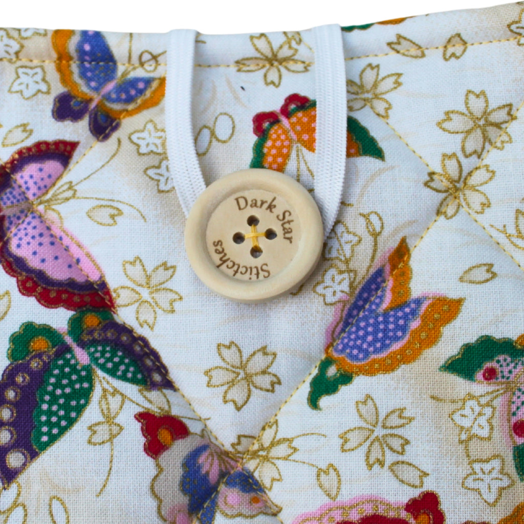 Close-up of button closure on handmade quilted booksleeve in cream butterfly cotton fabric