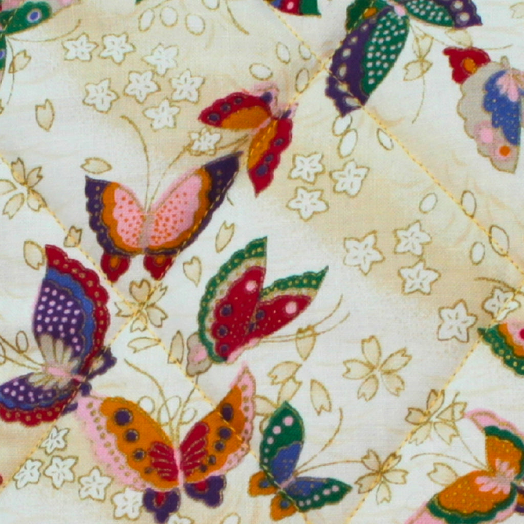 Close-up of multi-coloured butterfly pattern on cream cotton fabric used in handmade quilted booksleeve set