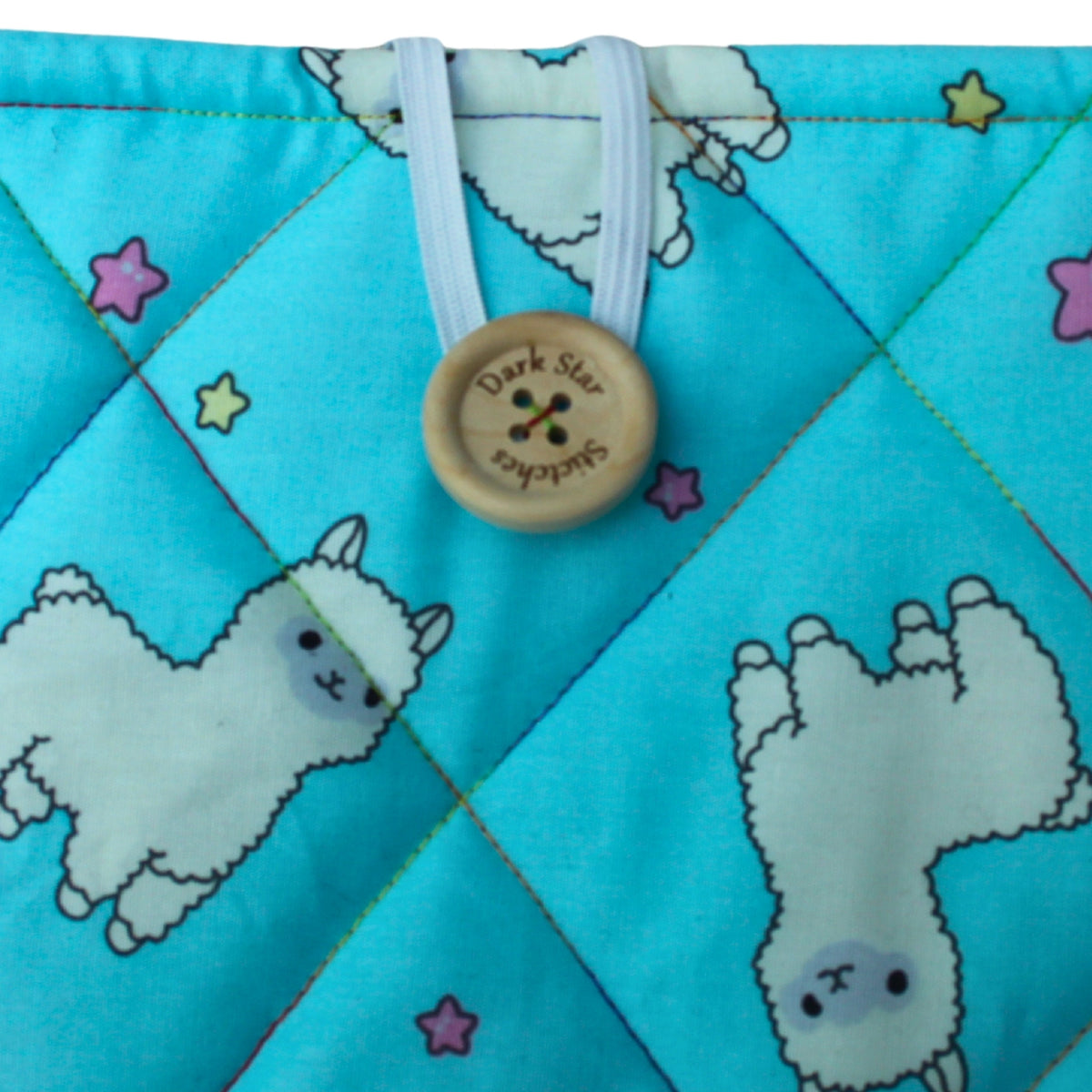 Close-up of button closure on handmade quilted booksleeve in bright blue alpaca cotton fabric