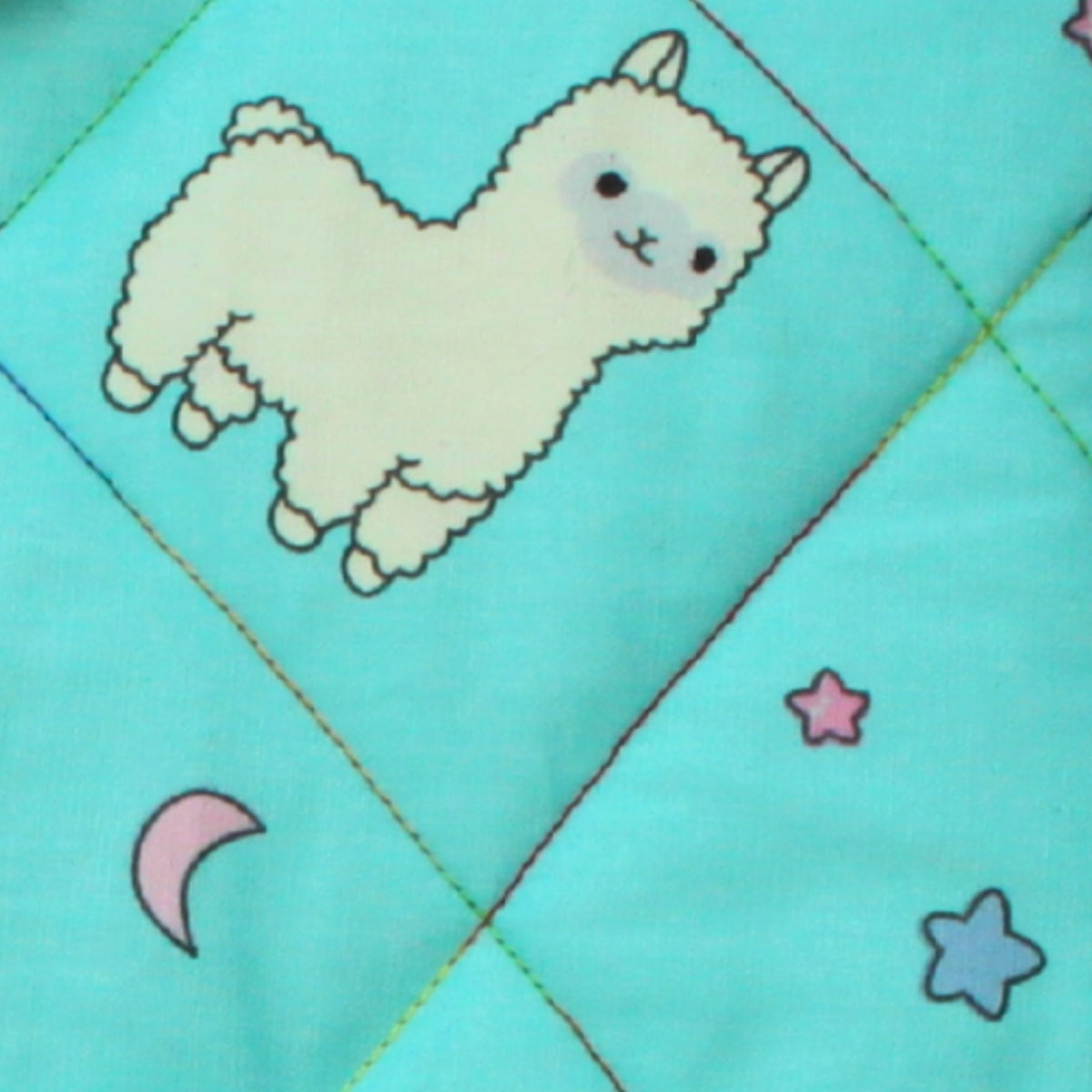 Close-up of cartoon alpaca pattern on bright blue cotton fabric used in handmade quilted booksleeve set