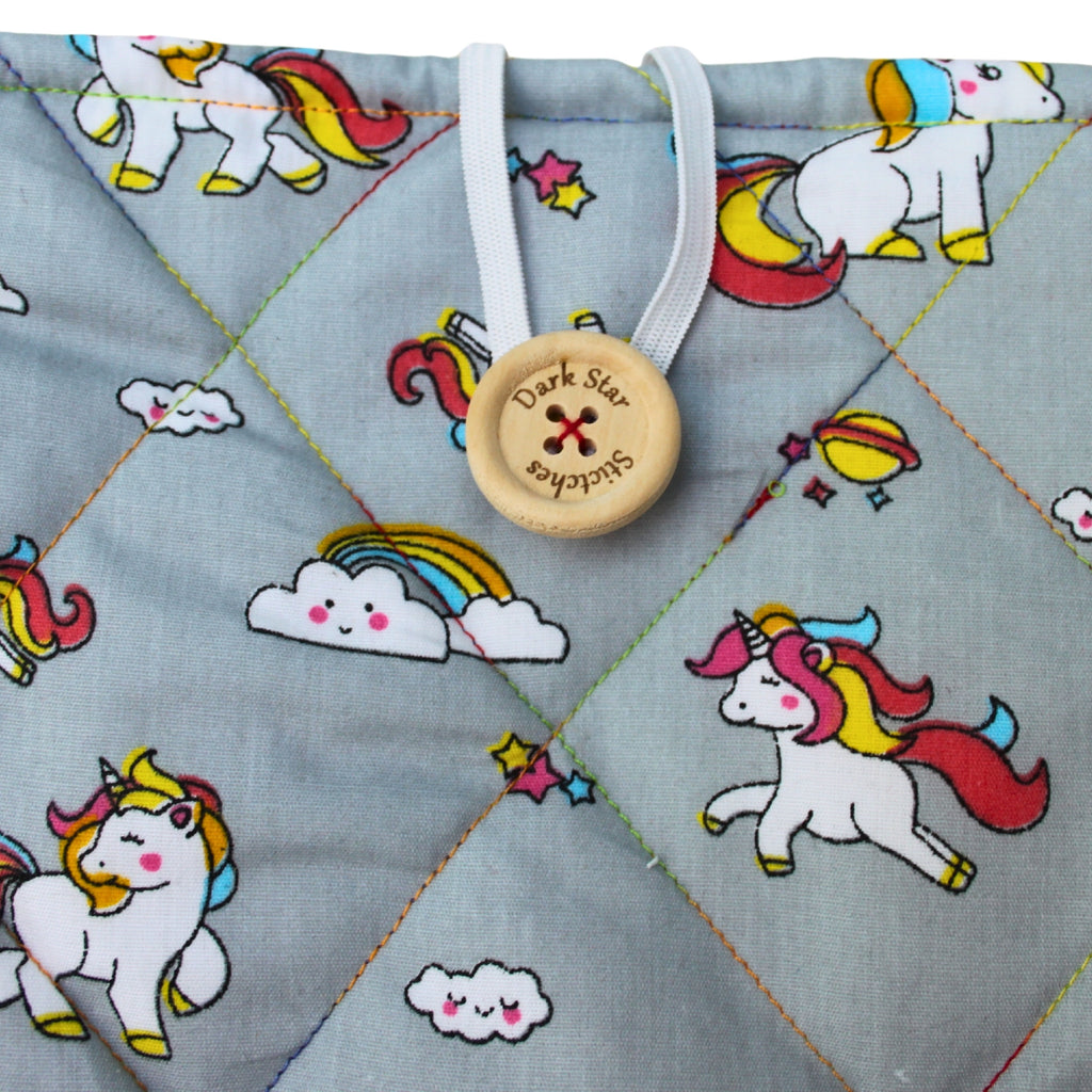 Close-up of button closure on handmade quilted booksleeve in grey unicorn cotton fabric