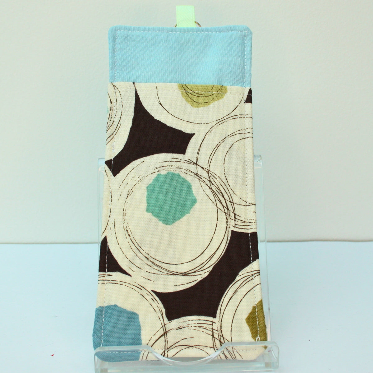 Reverse of handmade double sided lanyard pocket in black circles and splodges on brown fabric, pale green ribbon — Dark Star Stitches