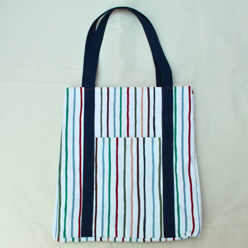 Side pocket detail on handmade fabric tote bag in multi-colour stripes with blue lining and navy strap — Dark Star Stitches