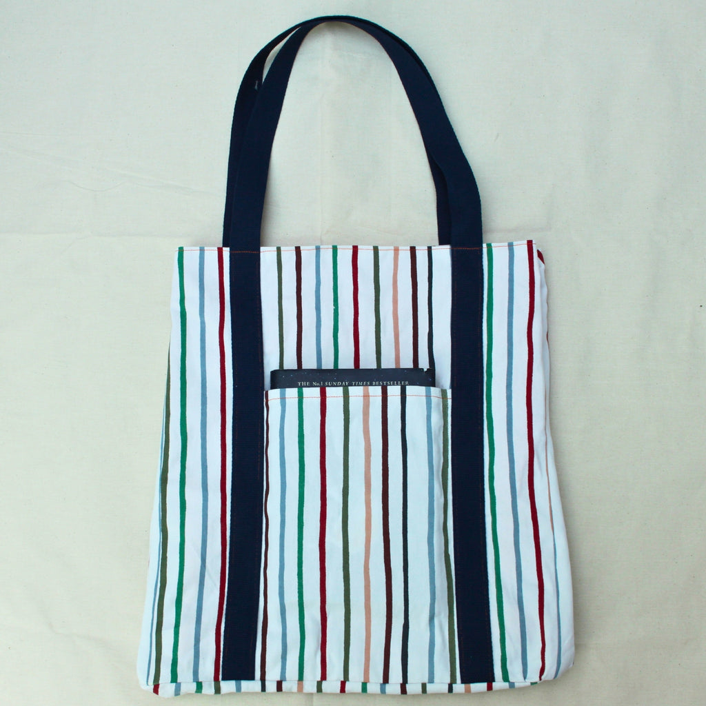 Pocket in use on handmade fabric tote bag in multi-colour stripes with orange lining and navy strap — Dark Star Stitches