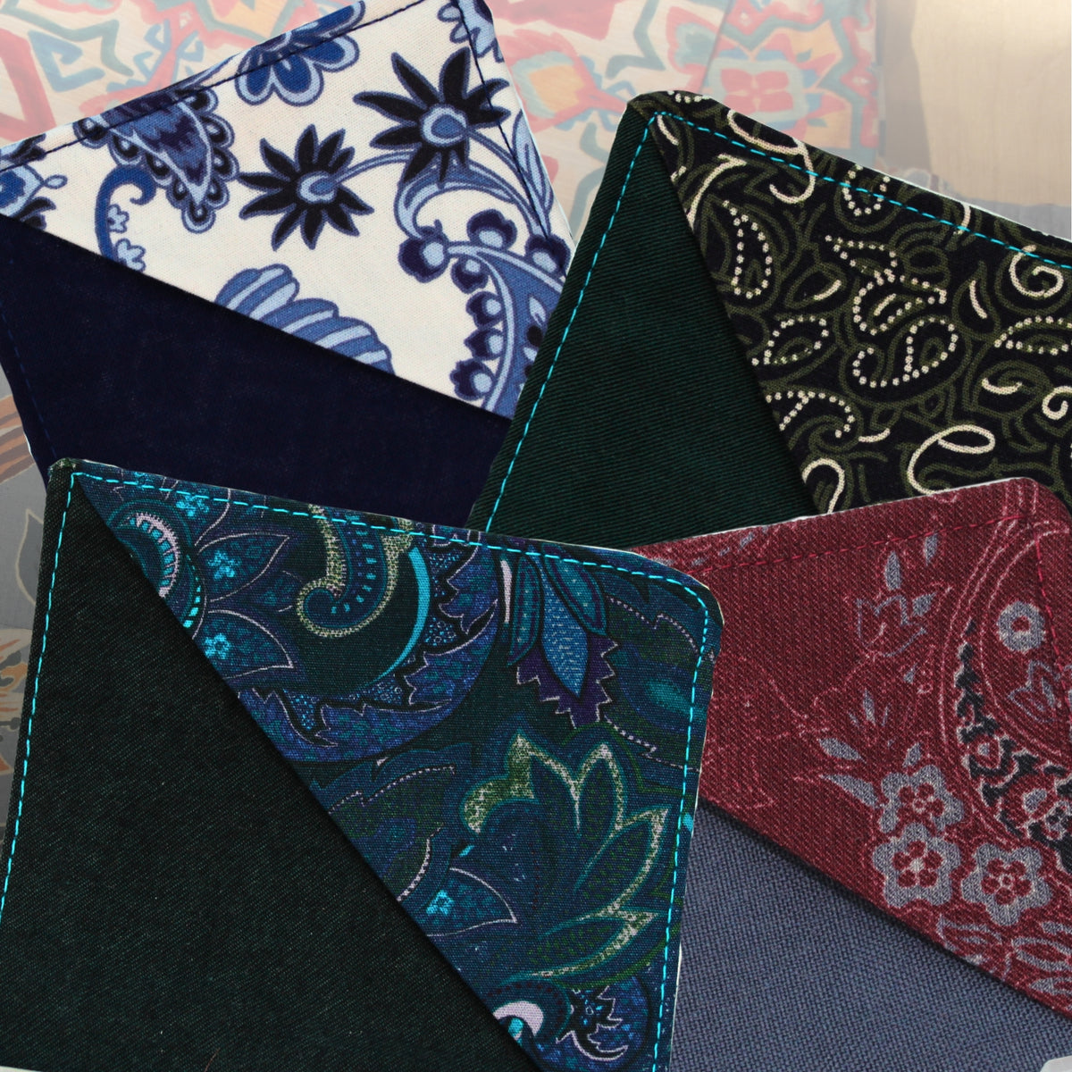 Four handmade fabric corner bookmarks fanned out, made from pre-loved paisley and floral fabrics in blue, teal, black and burgundy — Dark Star Stitches Second Chapter collection
